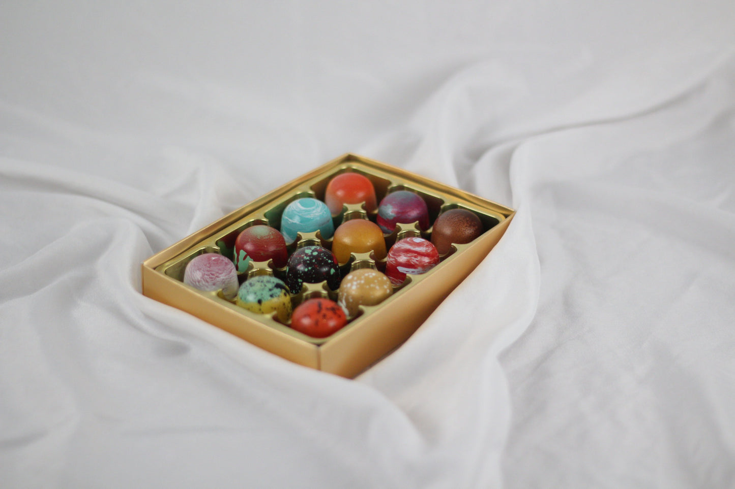 Box of colorful chocolates on a white fabric background
