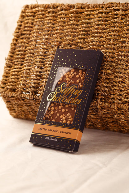 A stack of luxury handmade chocolate bars with different flavors, each bar is individually wrapped in a decorative paper with a brand logo visible on the top.