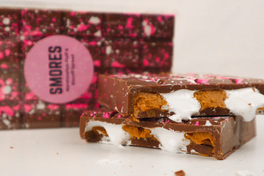 Chocolate bar with marshmallows and cookies in front of a Smores branded box.